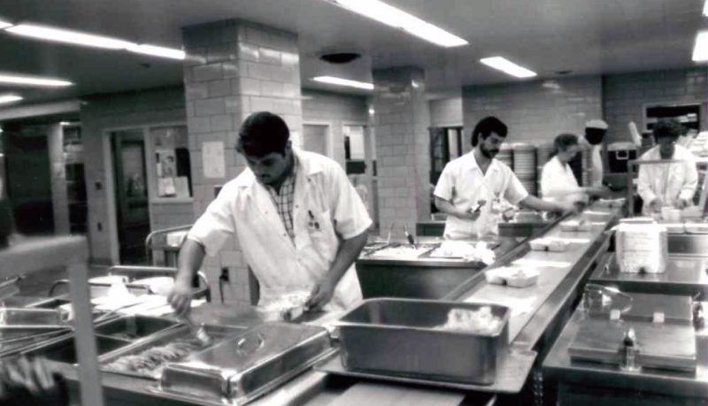 50th Anniversary: Black and white image of men working in a cafateria setting