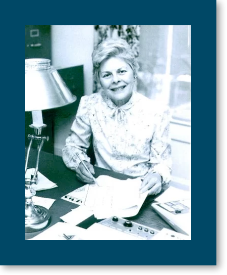 Our History: Ms Anna Pat Bailey sitting at a desk with paperwork in front of her
